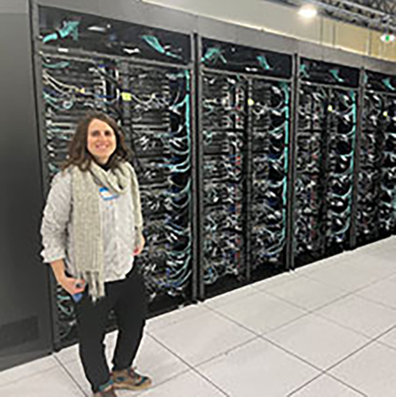 Laura de Sousa Oliveira, a UW assistant professor of inorganic chemistry, received a five-year, $874,296 DOE grant to study thermoelectric performance. The grant begins Sept. 1 and runs through Aug. 31, 2028. Here, she poses with the Derecho supercomputer at the NCAR-Wyoming Supercomputing Center in Cheyenne, which will be used for part of the research. (UW Photo)