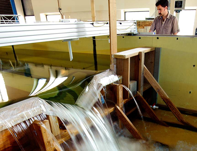 Researcher next to flume with water flowing