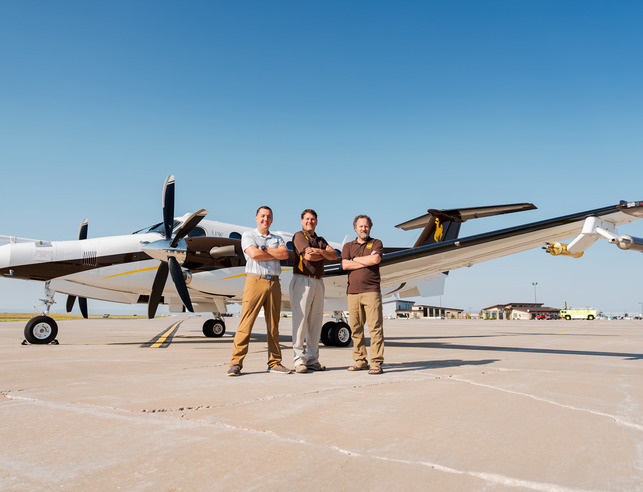 Three researchers in front of plane