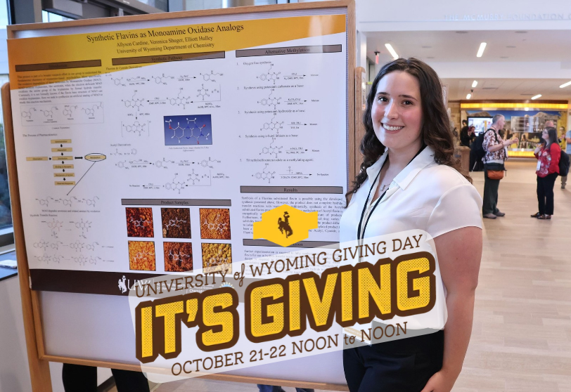 Student smiling at the camera standing next to a scientific poster. There is a small crowd visible behind in the atrium of the UW Gateway Center