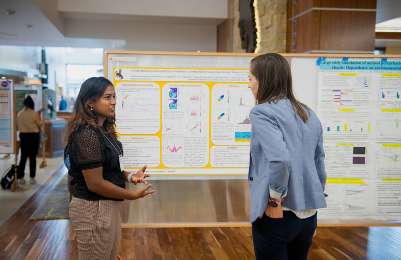 A UW student and UW community member discuss a research project at an event on the University of Wyoming campus.
