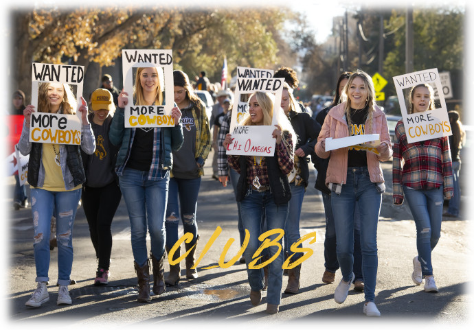 students in a parade holding wanted...more cowboys posters