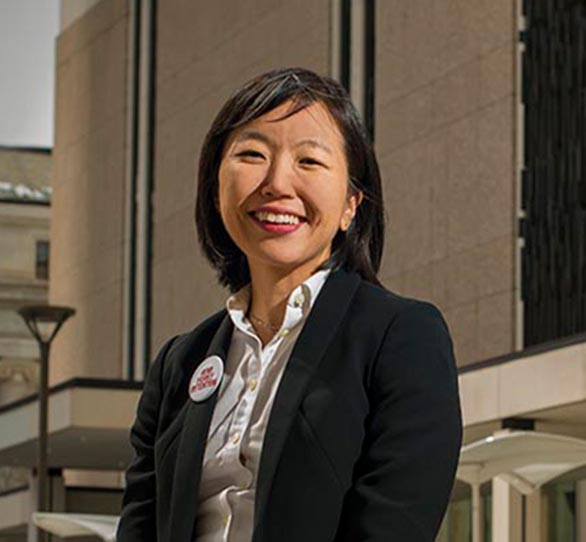 An Asian-American woman wears a black blazer and white shirt outside a university of Wyoming building.
