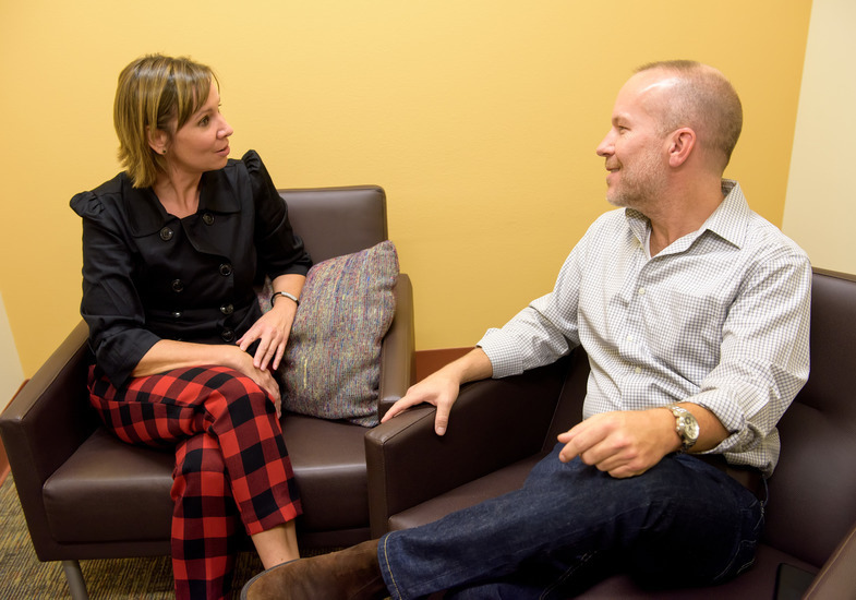 Two people talking in an office setting – A woman and a man seated in chairs, engaged in conversation.