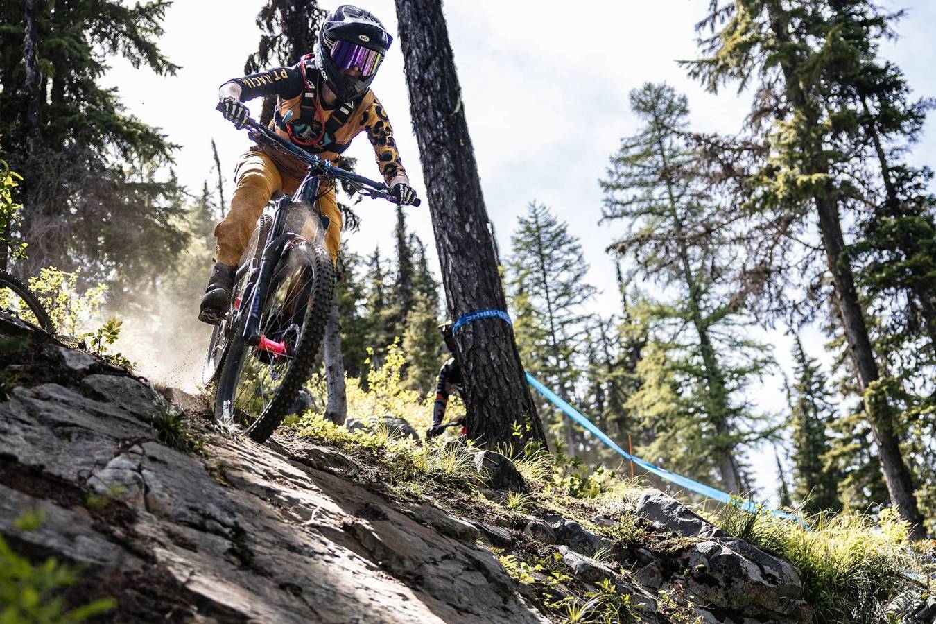 A biker riding down a steep hill in a forest