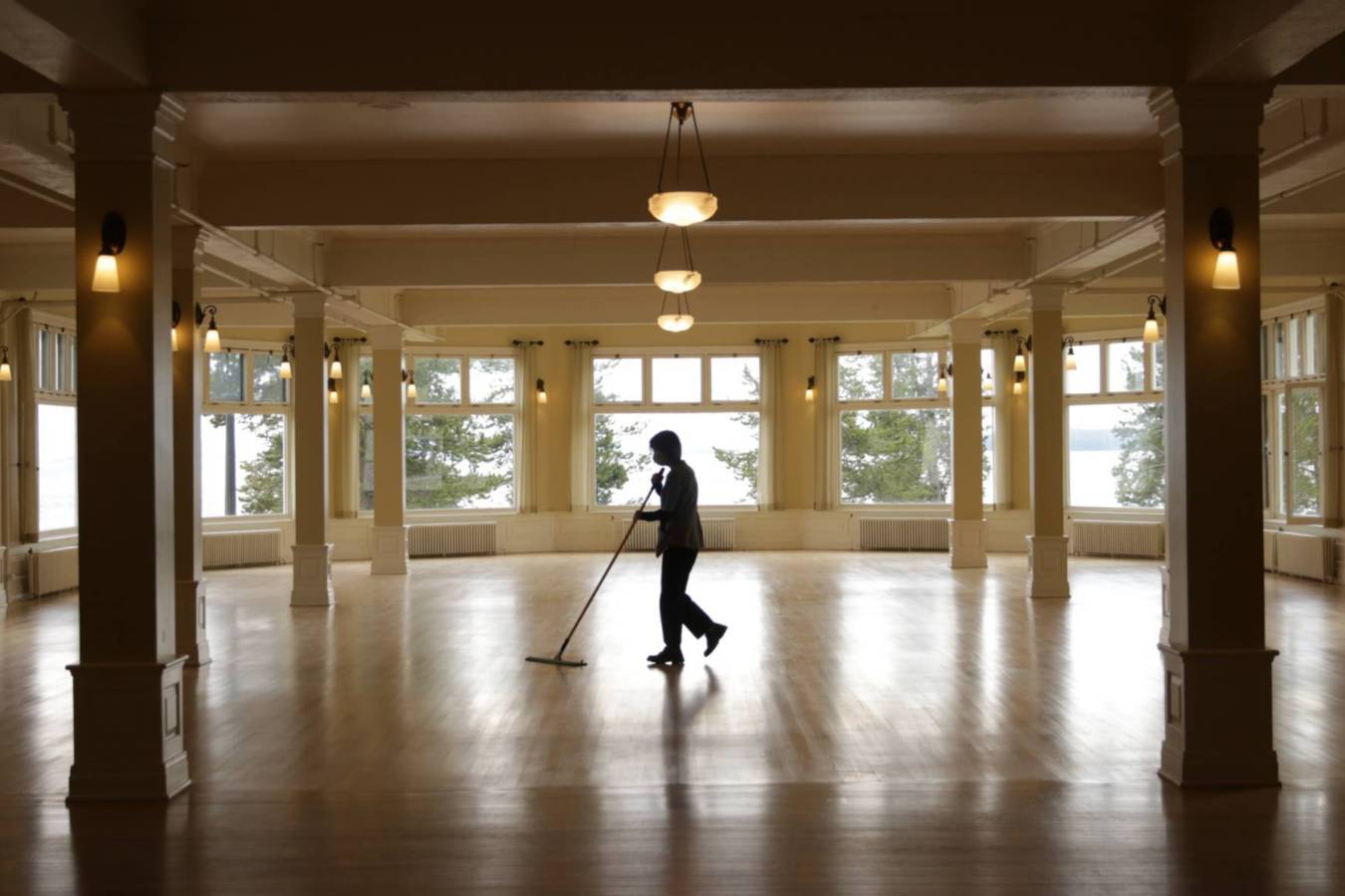A person with a broom in an empty hall