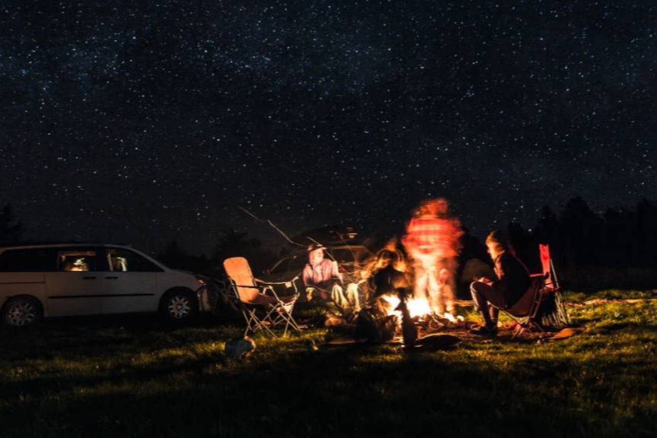 A group of people sitting around a campfire at night