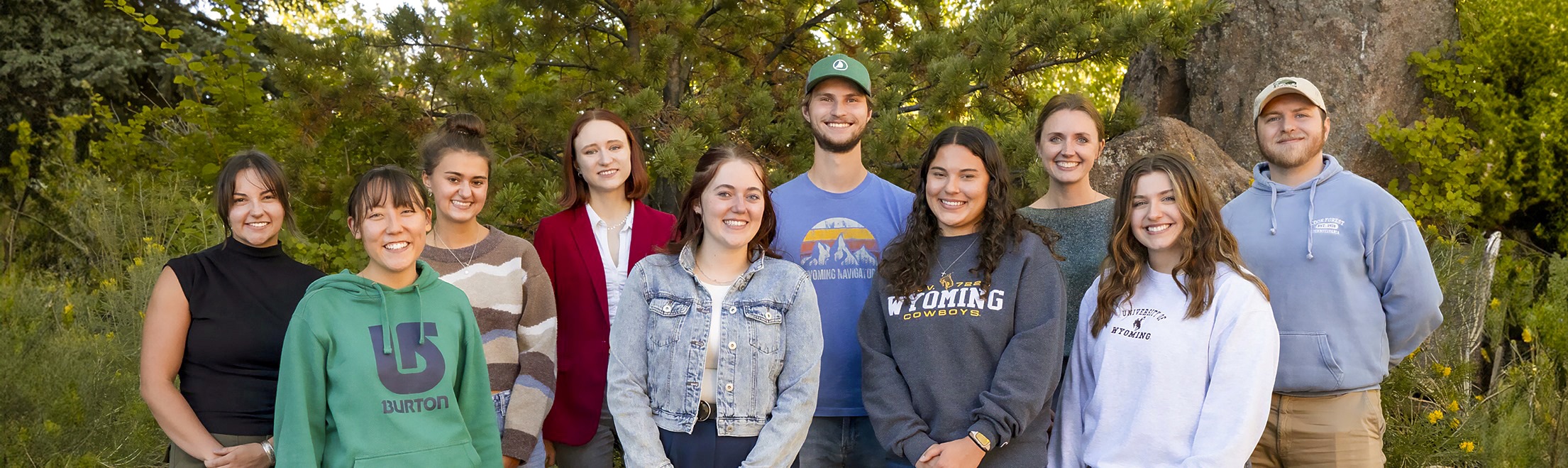 Lambda Pi Eta students smiling at the camera on a summer day outside