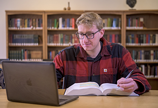 Male student doing work on a laptop computer.