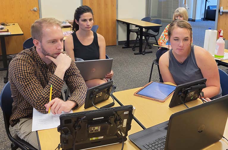 Students at a table looking into a monitor. 