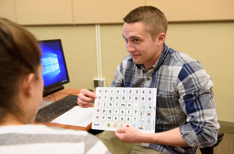 Man showing students a alphabet chart.