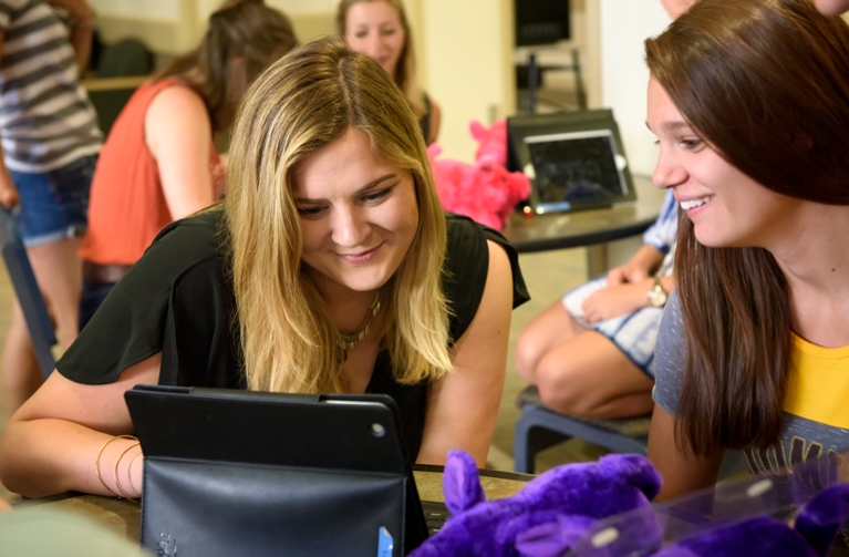 Two female students looking into a monitor.