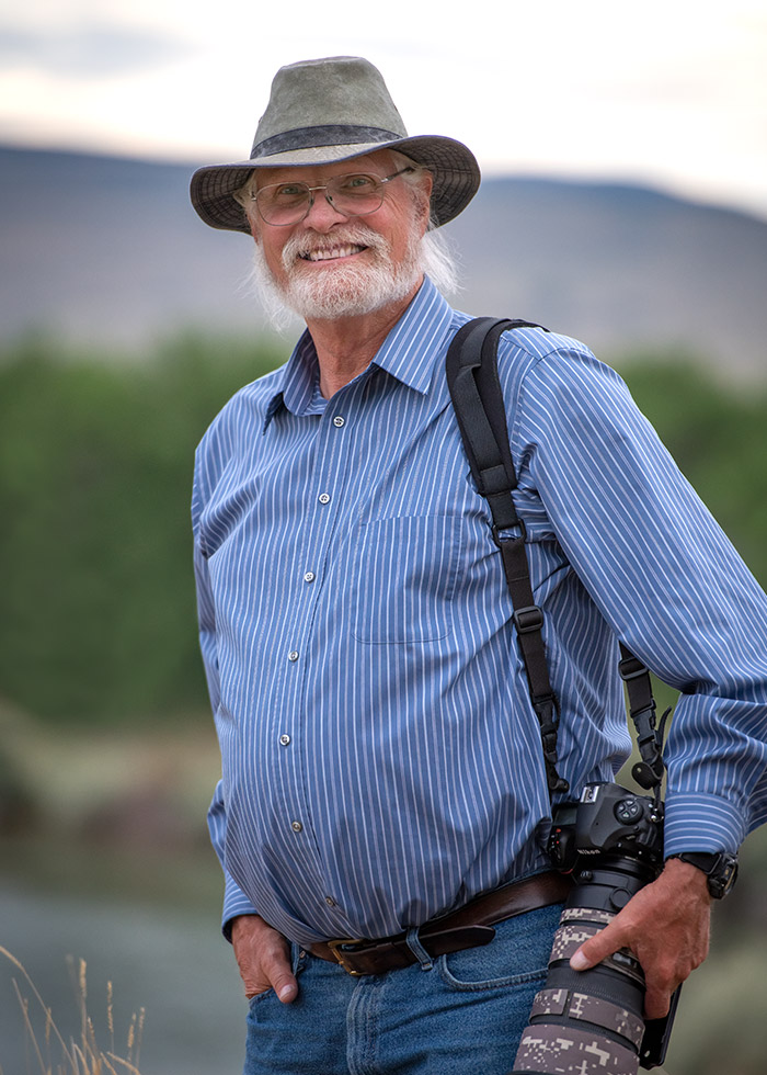 Jeb Schenck outside of his home in a field with a large camera