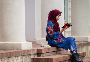 MFA graduate Rabbia Khalid reads on the porch of the Cooper House.