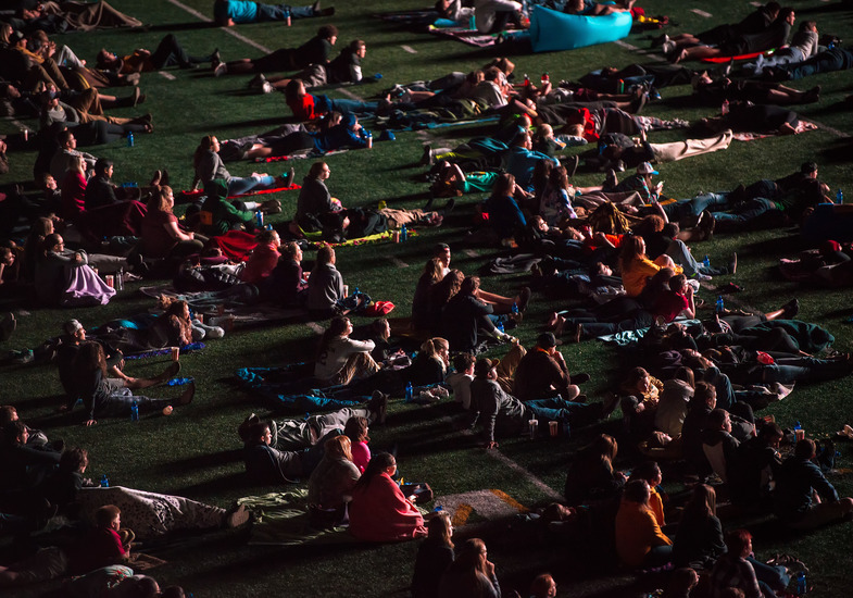 UW students and community members lay and sit on the field at War Memorial Stadium to watch a movie on the jumbotron