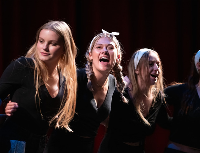 Three female students on stage dancing and singing