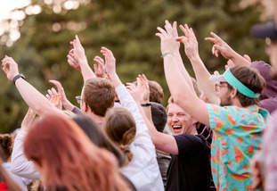 UW students raise their hands in the air and cheer at an University of Wyoming on-campus concert