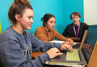 Three UW students work together on their laptops