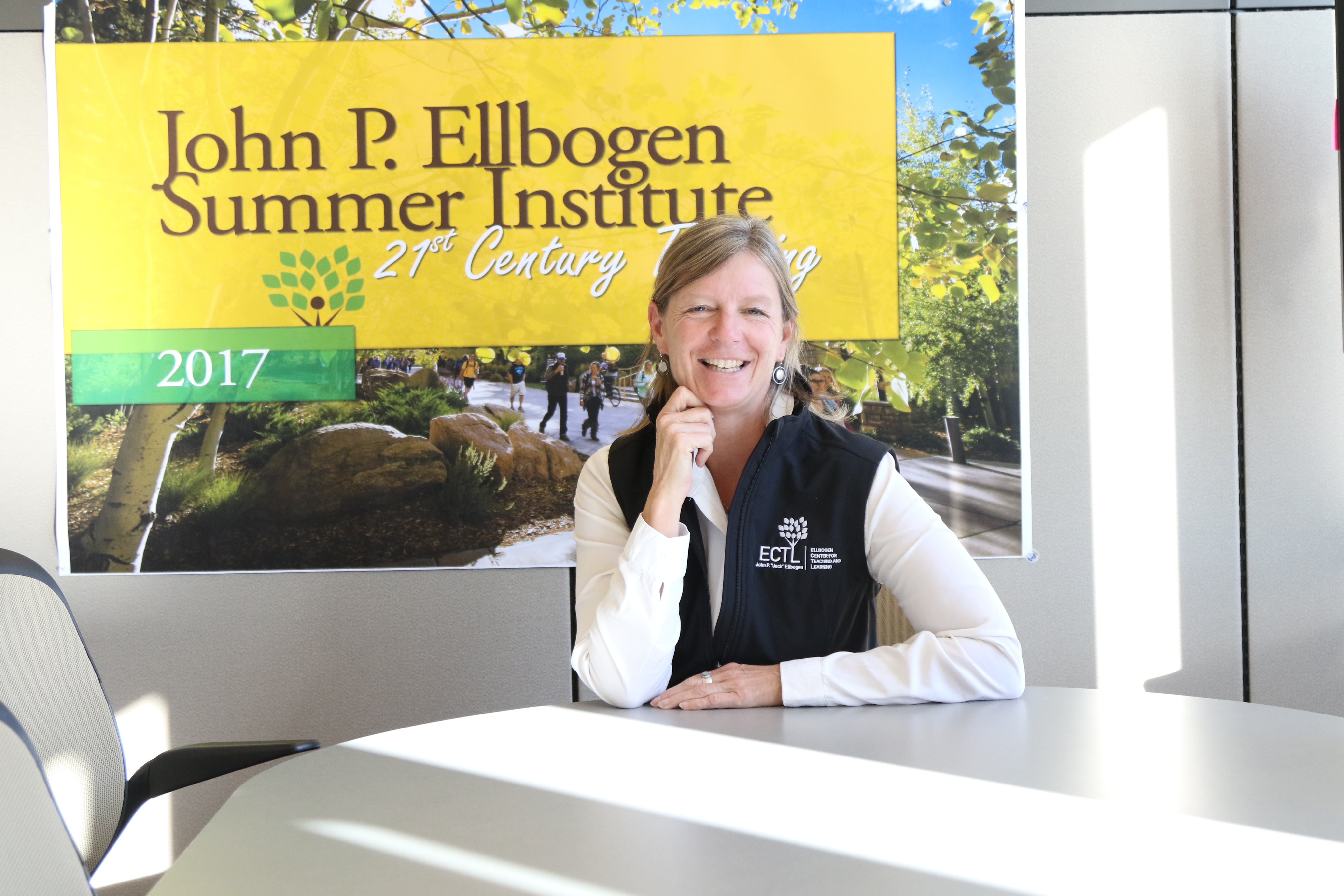 Janel Seeley smiling in front of an ECTL Summer Institute Banner