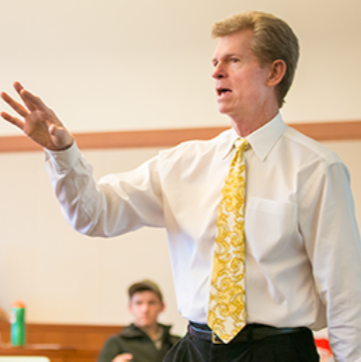 a professor at the University of Wyoming is lecturing with his hand held up.