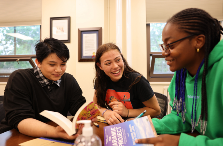 Three Students reading a book in the poke pride center
