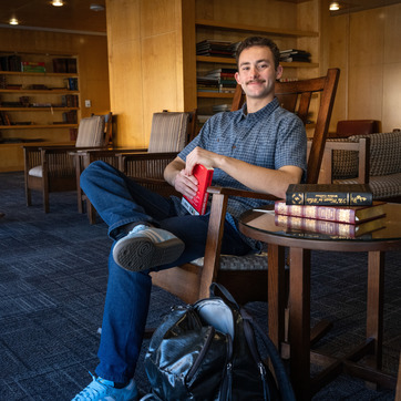 Male student sitting on chair with books
