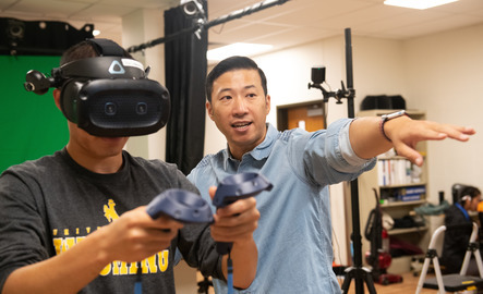 A UW faculty member assists a UW student with new virtual reality technology.