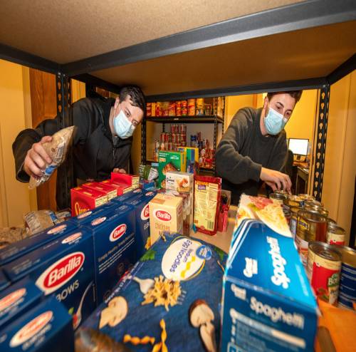 Two students stocking food pantry shelves