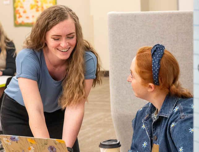 Two students talking at a desk