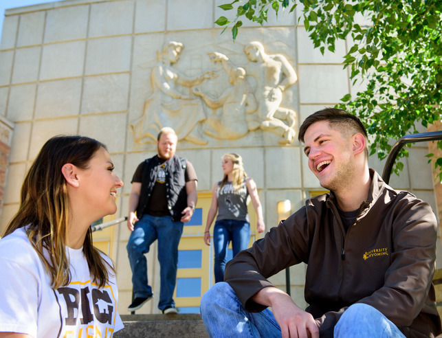 Two students sitting outside talking and laughing