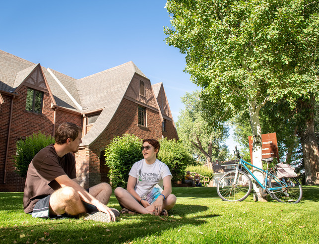 Two students sitting on grass talking