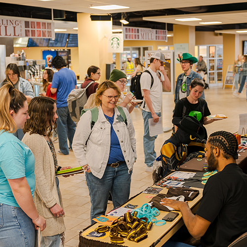 Denim Day participants speak with resource tables in the Union breezeway.
