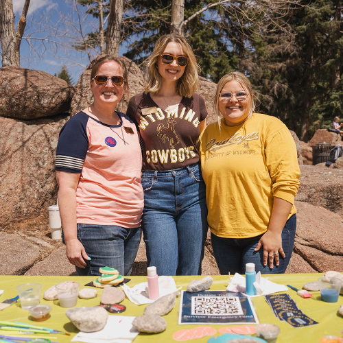 Violence prevention volunteers pose for a photo in front of a kindness rock painting activity