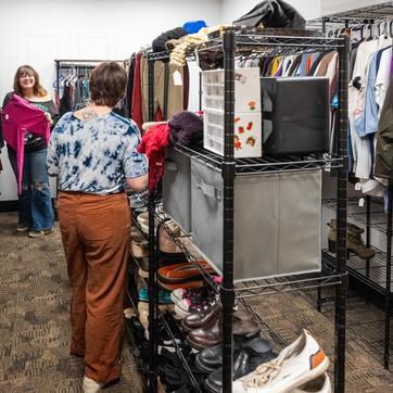 One student showing another some pink pants she found in the clothing closet