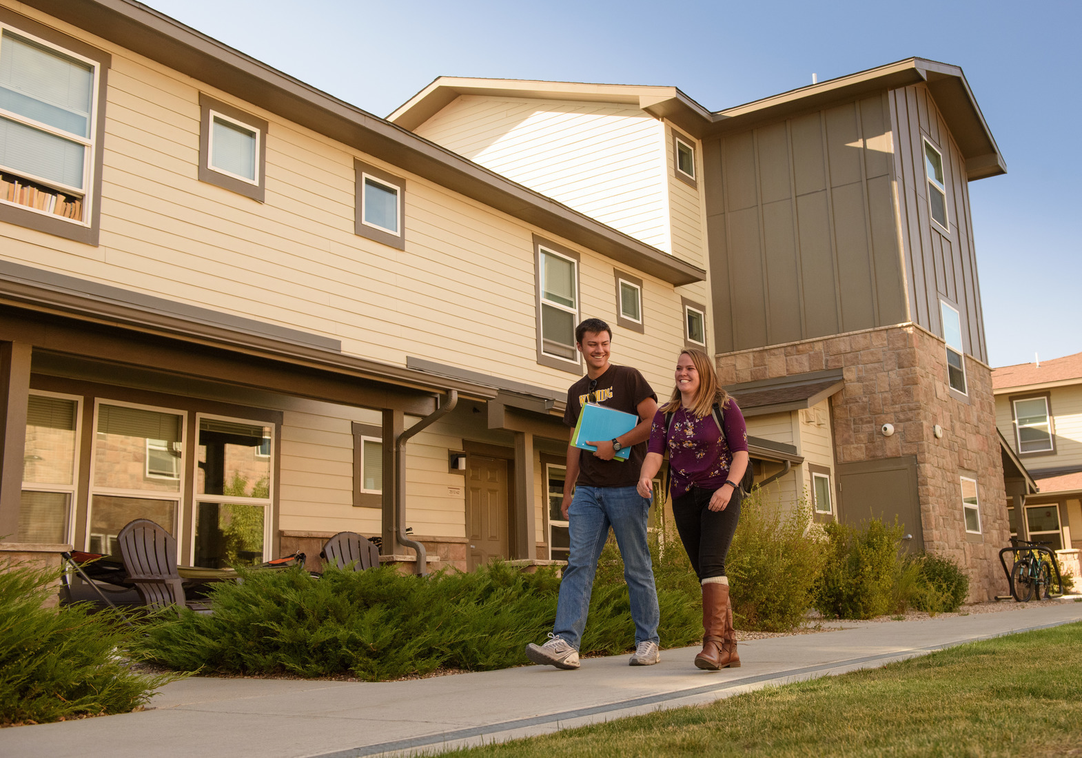 Two Students walking in front of the Bison Run apartments