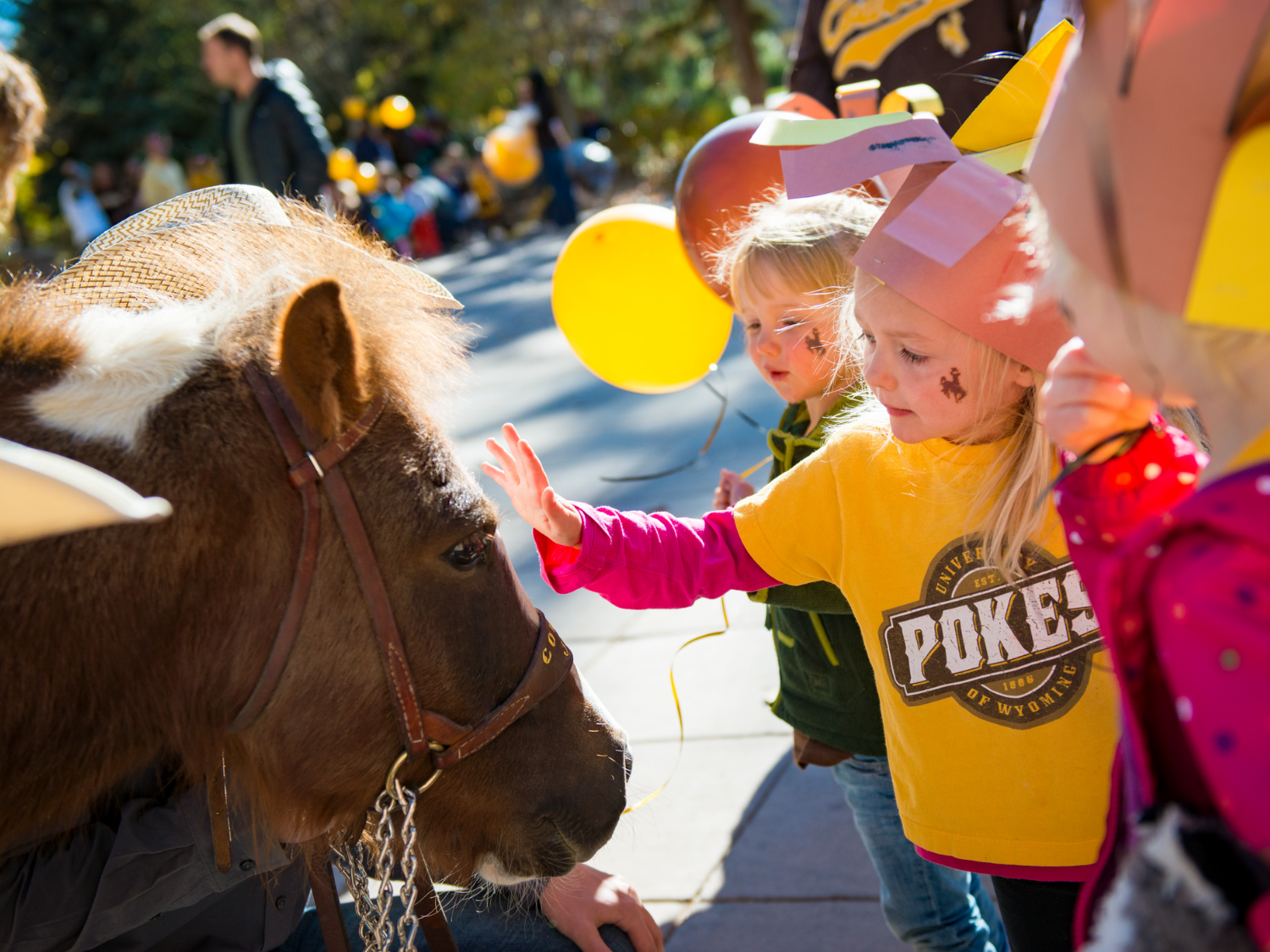 children at parade petting a horse