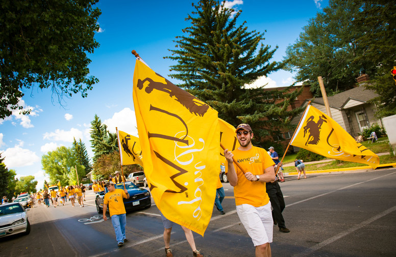 Students in a parade waving UW flags