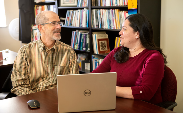 Two people working at a laptop.