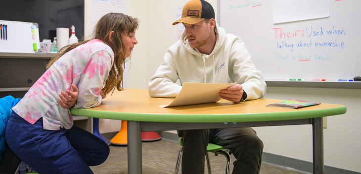 Education student working with a young student at a table