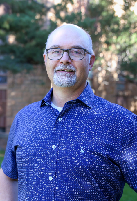 Heath Hornecker in a blue patterned button up in front of McWhinney Hall