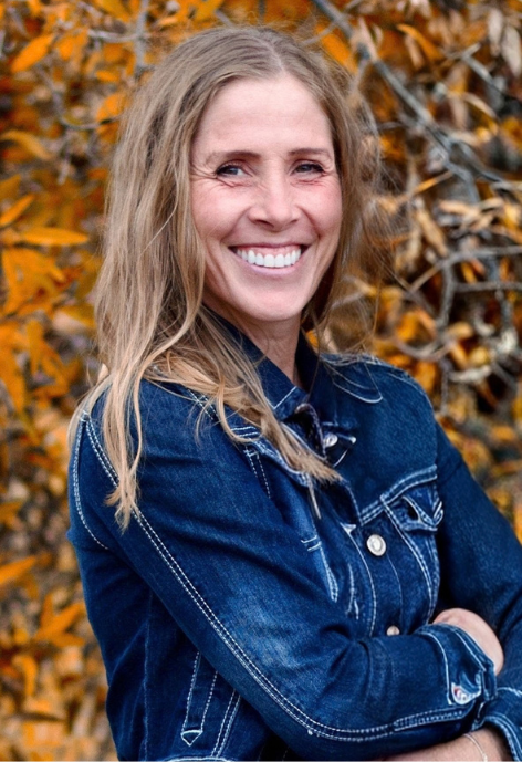 Marsha Gull in a denim jacket in front of fall leaves 