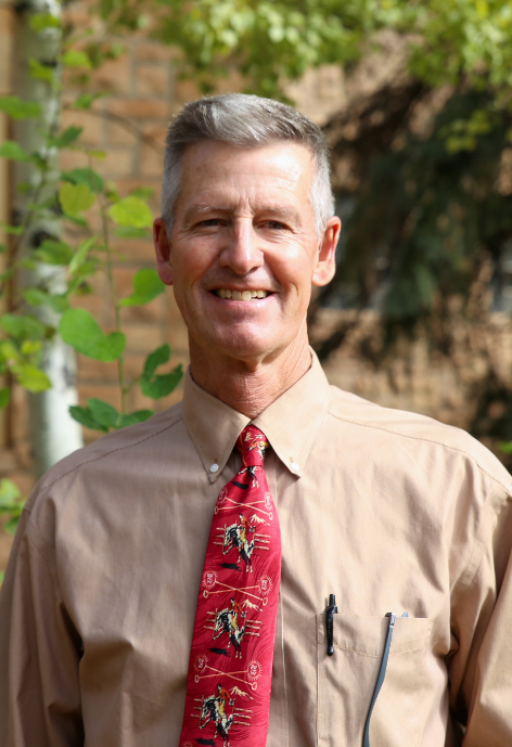 Ty Berry in a brown button up with a red tie with bronco riders on it, in front of the Education Building