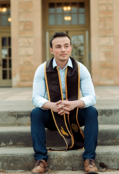 Zachary McInerney in front of the Arts and Sciences Building wearing a UW Brown and Gold graduation stole