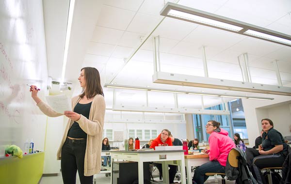 High school teacher teaching at white board.