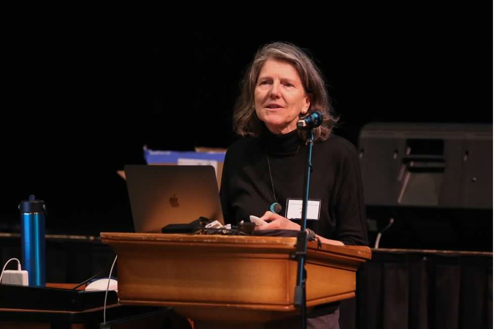 A woman standing behind a podium with a dark background