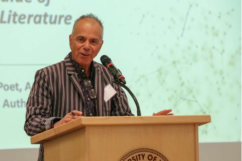 A man speaking at a podium with a green background