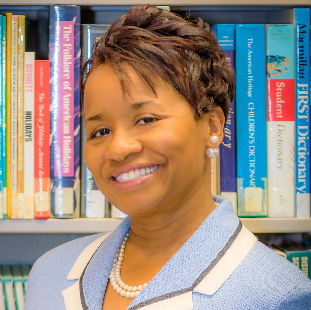 professor in a library smiling at the camera