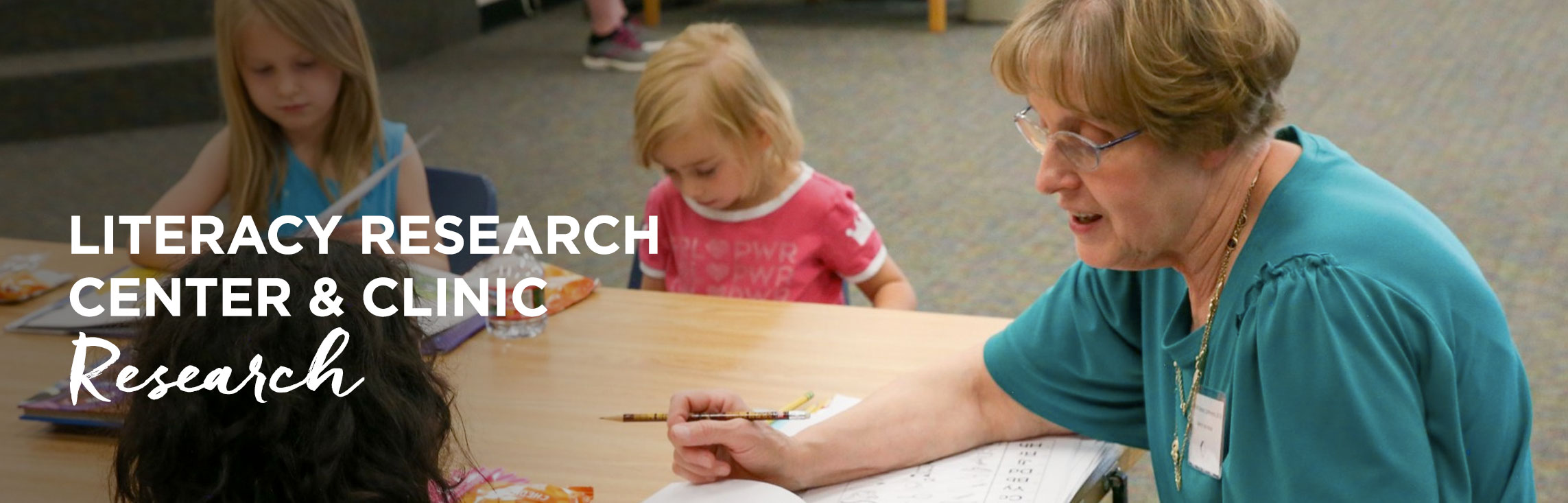 Teacher tutoring students with wording: Literacy Research Center & Clinic Research