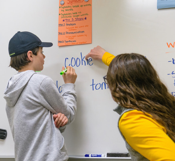 Teacher showing student how to write on white board
