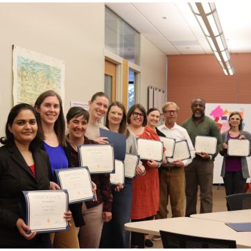 Faculty members holding up certificates of program completion